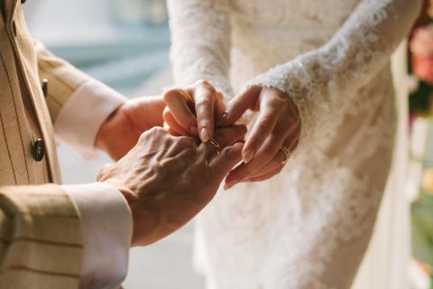 bride putting ring on groom's finger rings exchange happy couple celebrating wedding outdoors in summer