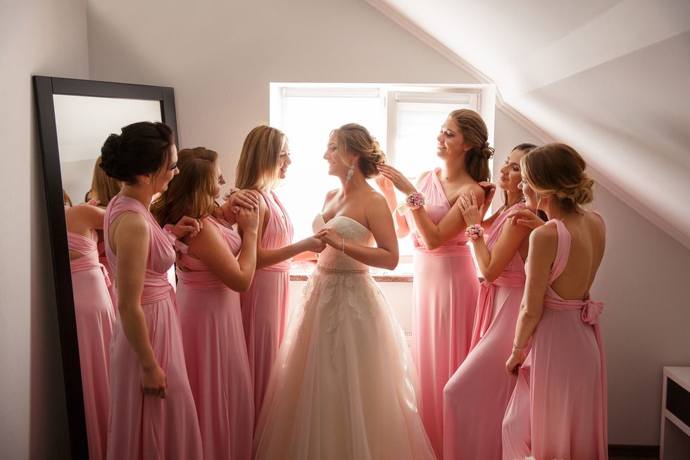 bride with bridesmaids posing in hotel or fitting room at wedding day