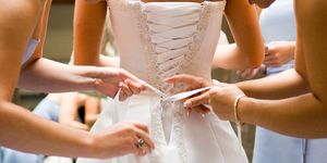 Bridesmaids help bride into her dress