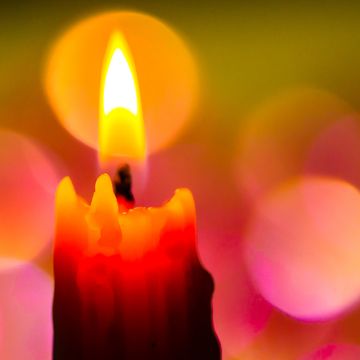 bright lighted candle with colourful background