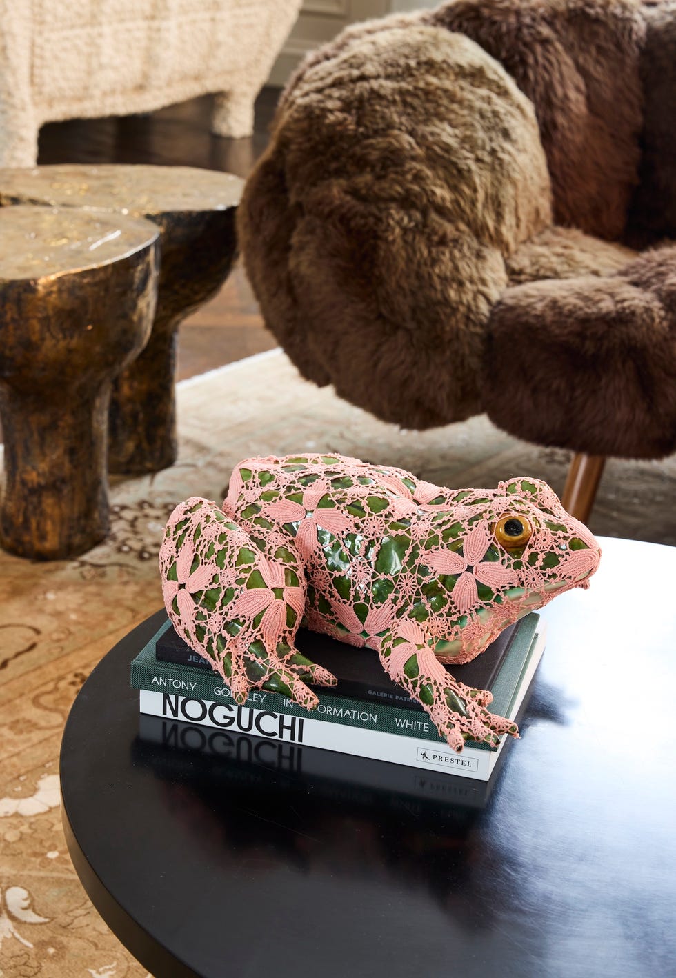 decorative pink frog sculpture placed on a stack of books on a coffee table