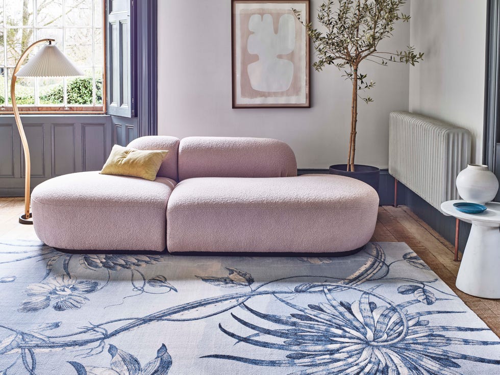 a blue and white patterned rug with curvy sofa in a living room
