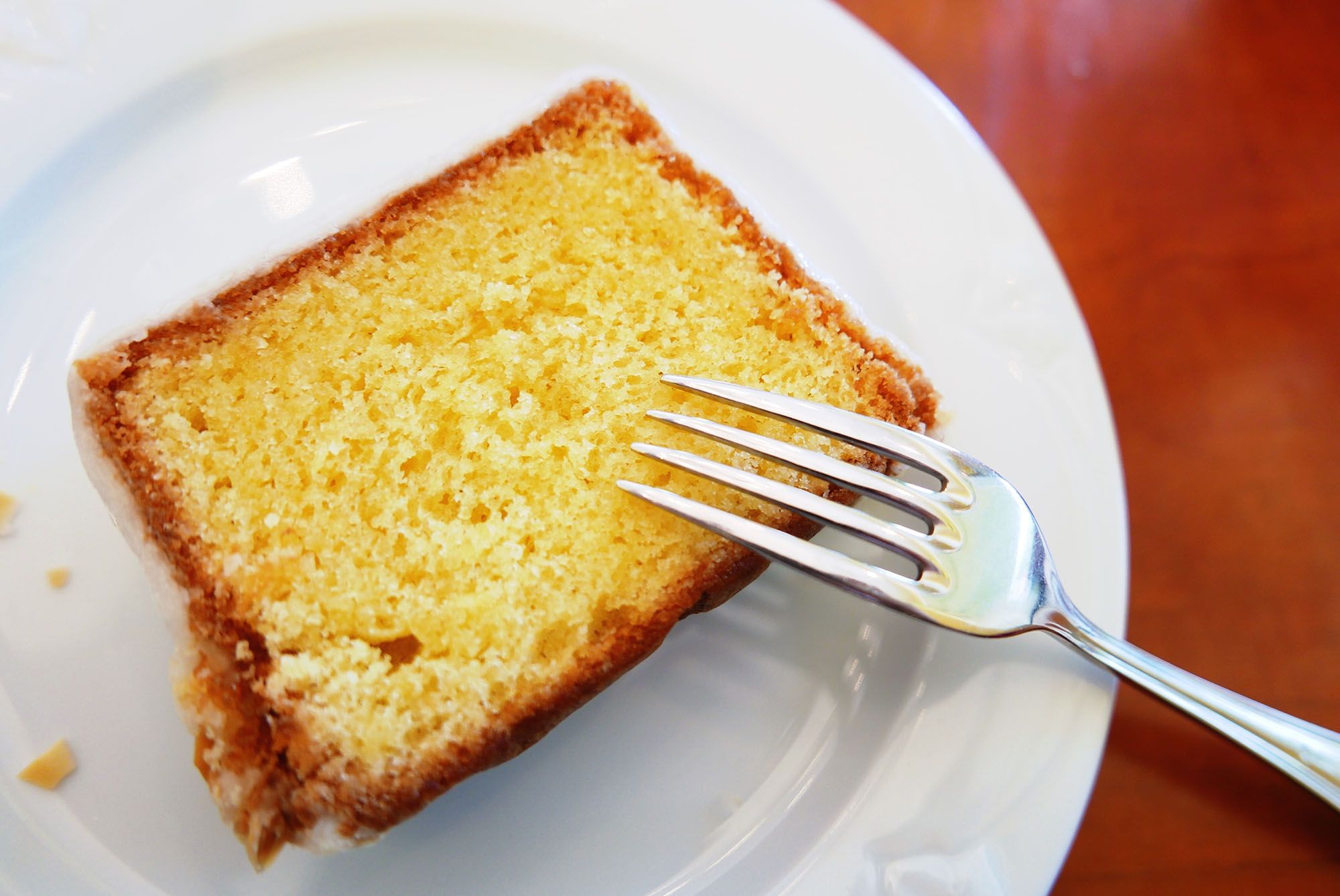 High Angle View Of Lemon Cake Slice With Fork In Plate