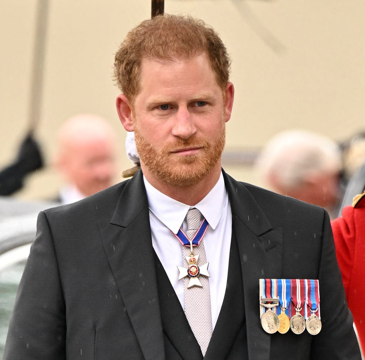 Prince Harry at Westminster Abbey during King Charles’ coronation in May 2023 prince harry walking as a guard holds an umbrella for him