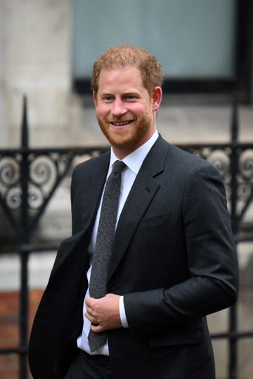 prince harry smiling for photographers as he walks into court