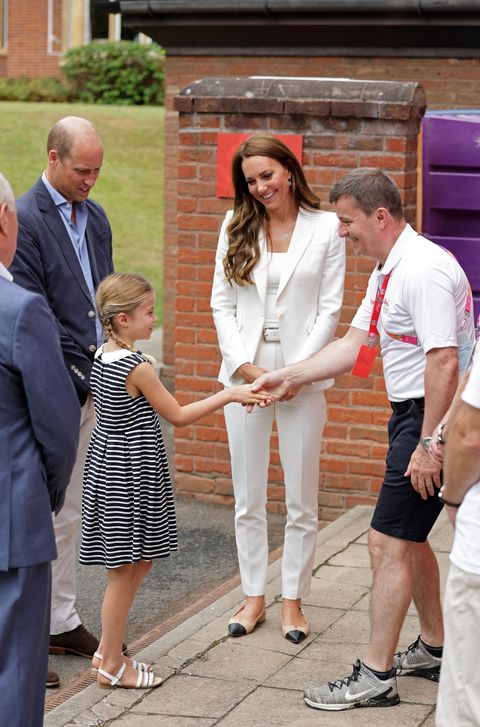 kate middleton pictured in a white suit at the commonwealth games event in birmingham wearing black and tan flats