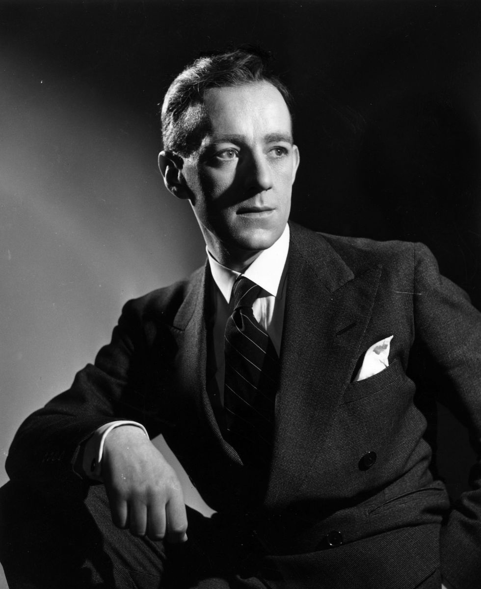 alec guinness posing for a portrait photograph in a suit and tie