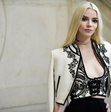 anya taylor joy wearing a dior dress for a photocall and posing in front of a marble staircase