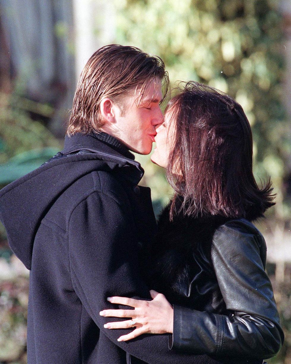 david beckham and victoria adams embrace for a kiss, both wear dark coats as they stand outside