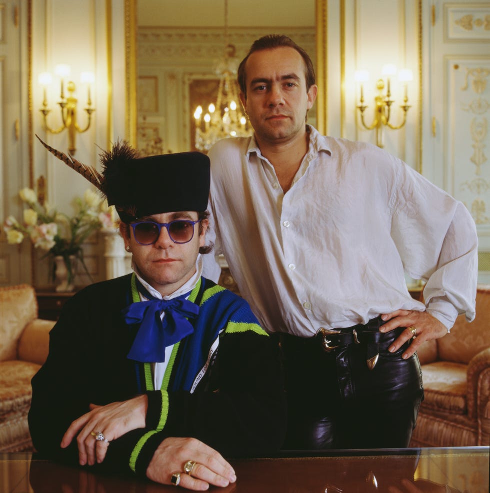 elton john and bernie taupin look at the camera while inside an ornate room