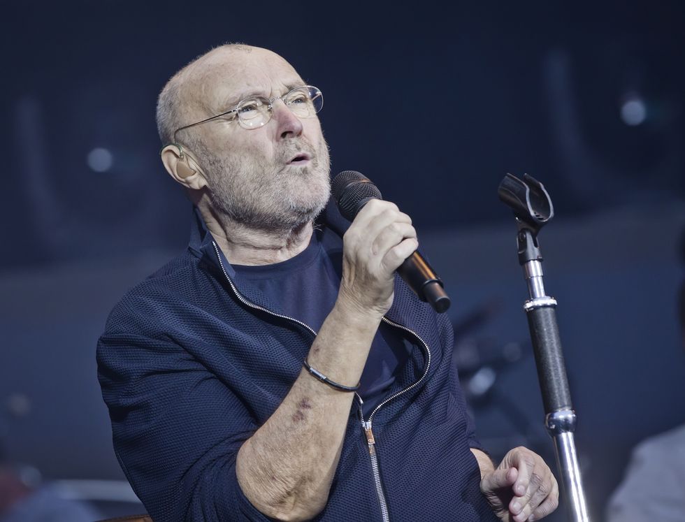 phil collins holding a microphone and singing