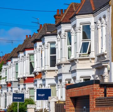 a row of typical british terraced houses around kensal rise in london with estate agent boards