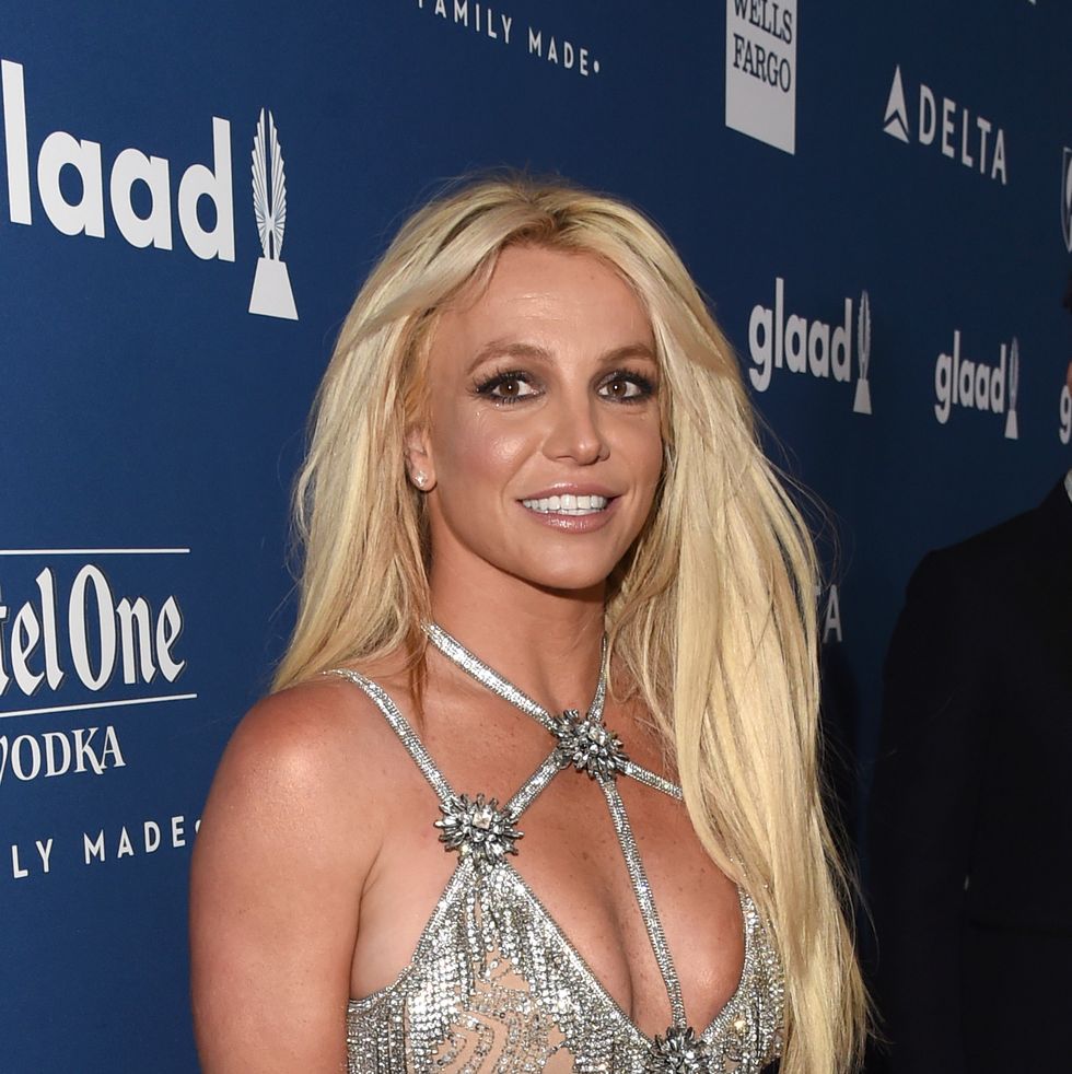 Britney Spears blickt in die Kamera und posiert auf dem Teppich, während sie ein Kleid mit silbernen Perlenausschnitten trägt