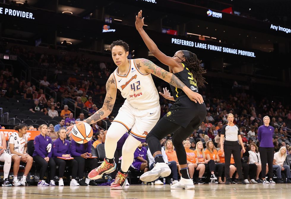 brittney griner, in a phoenix mercury jersey, playing offense in basketball against chiney ogwumike, wearing a los angeles sparks jersey
