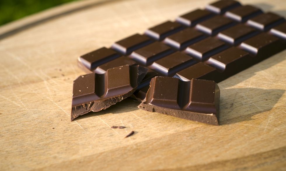 a broken bar of dark chocolate on a wooden cutting board