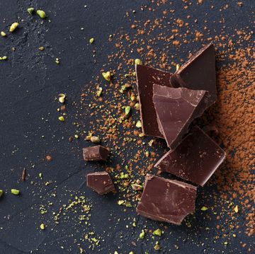 Broken chocolate pieces and cocoa powder on black background