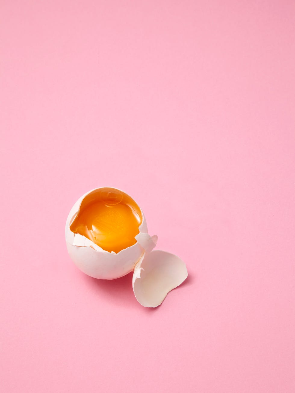 broken egg on pink background