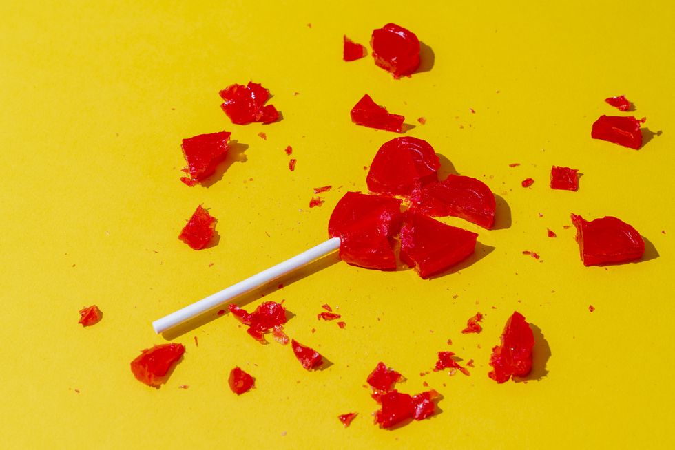 broken red heart shaped lollipop on yellow background
