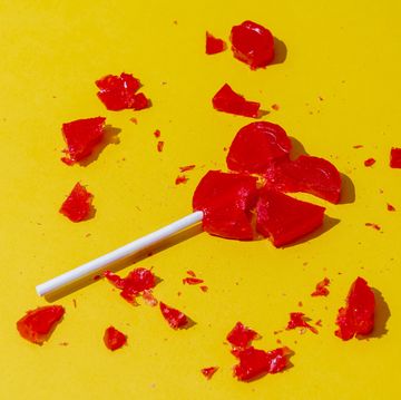 broken red heart shaped lollipop on yellow background