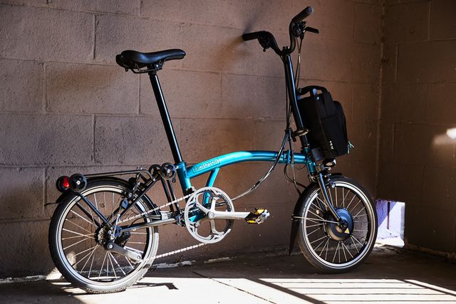 folding brompton electric bike parked against a wall