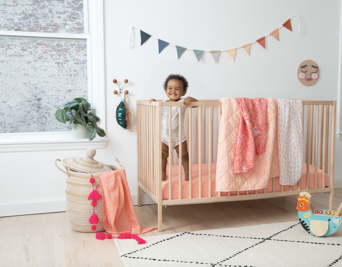baby in crib with blush blankets
