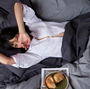 woman lounging in brooklinen sateen sheets on bed