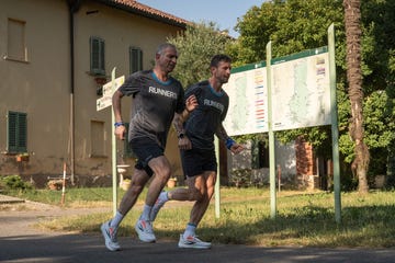 two runners in sportswear jogging past a directional sign in an outdoor setting