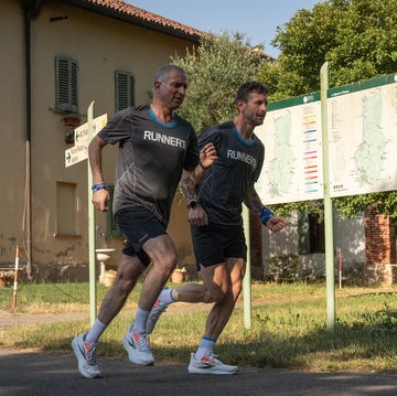 Test Brooks Ghost 17 two runners in sportswear jogging past a directional sign in an outdoor setting