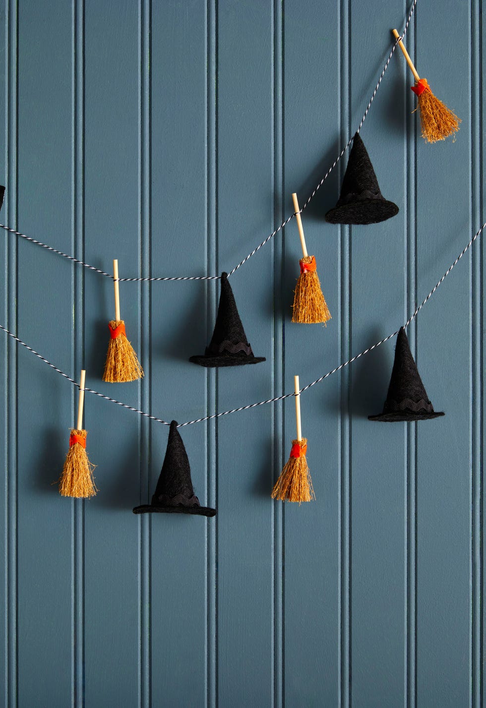 mini witch hats and brooms strung on bakers twine to form a garland