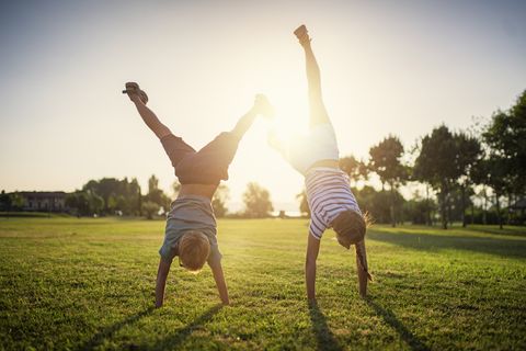 Brother and sister standing on hands on grass
