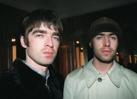 liam and noel gallagher of rock band oasis looking forward at a camera with emotionless expressions