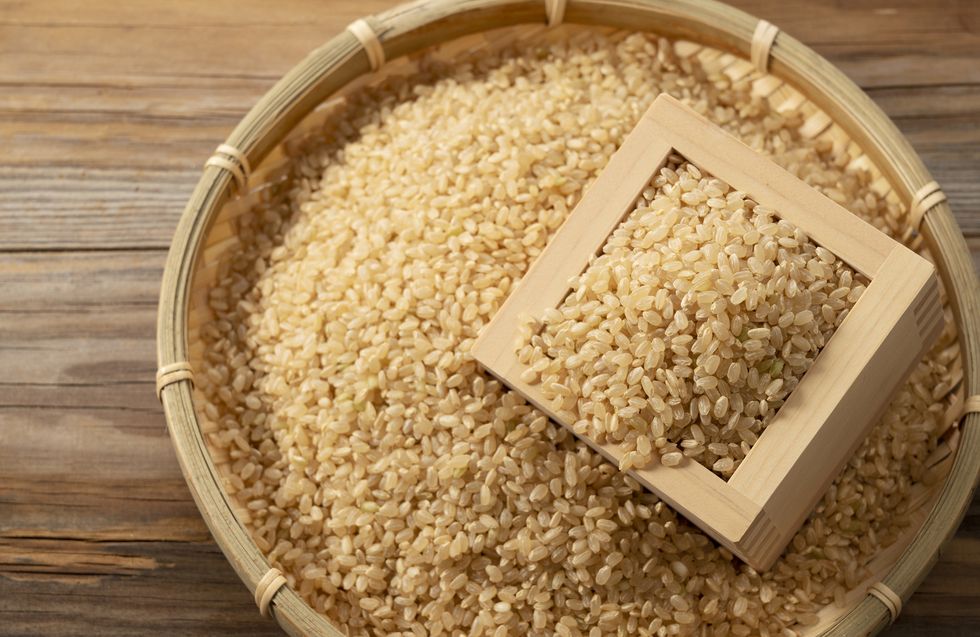brown rice in a wooden box set against a wooden background