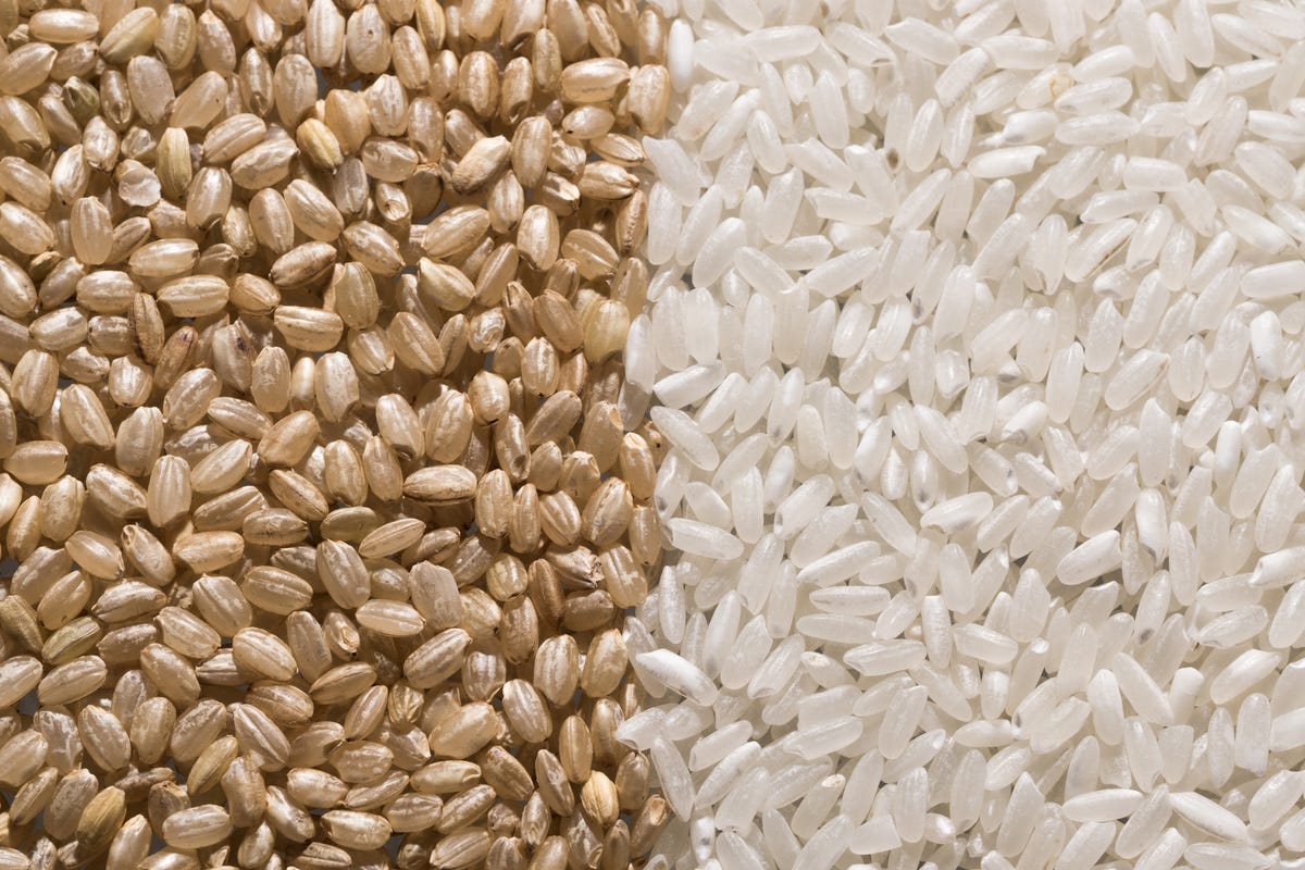 grains of raw brown rice next to grains of raw white rice