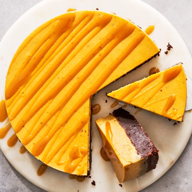 brownie bottom pumpkin cheesecake with a caramel drizzle on a marble platter