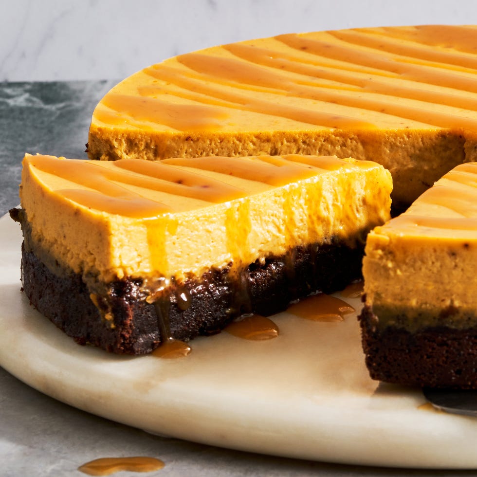 brownie bottom pumpkin cheesecake with a caramel drizzle on a marble platter