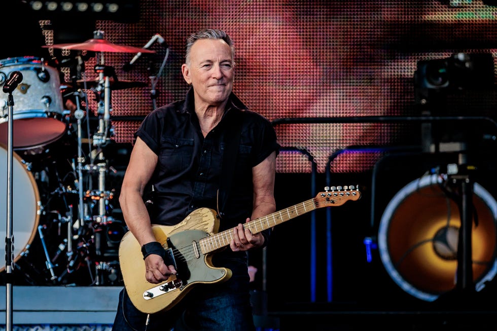 bruce springsteen plays electric guitar while standing on a stage