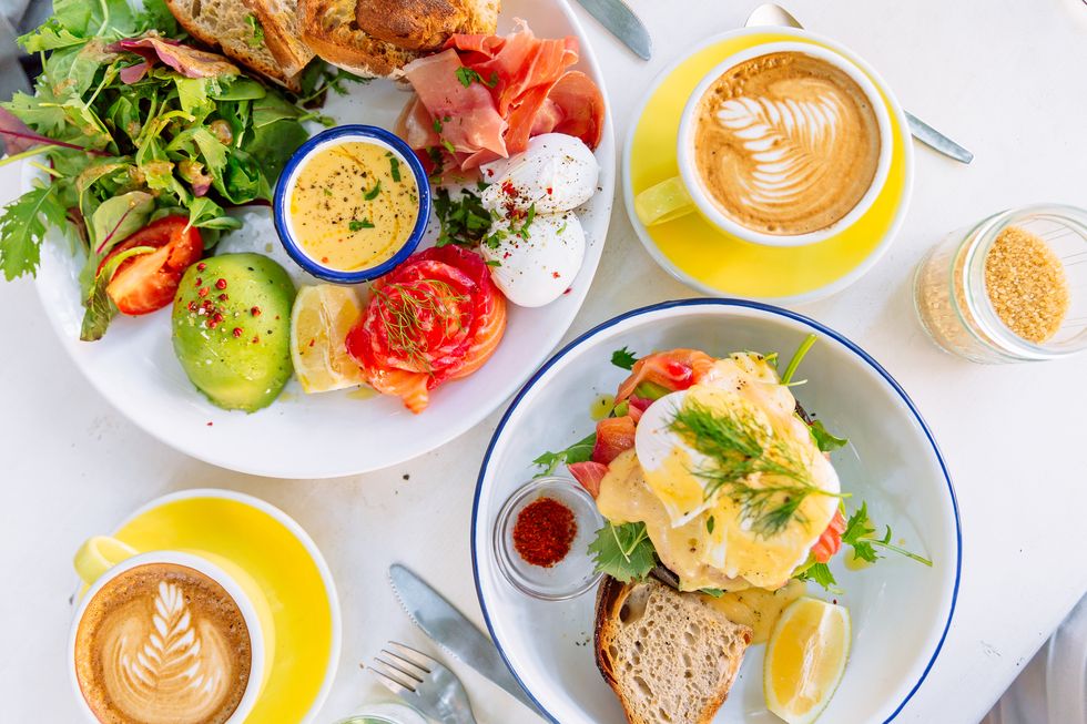 brunch with eggs benedict, salmon, avocado, salad and coffee served at the restaurant, directly above view