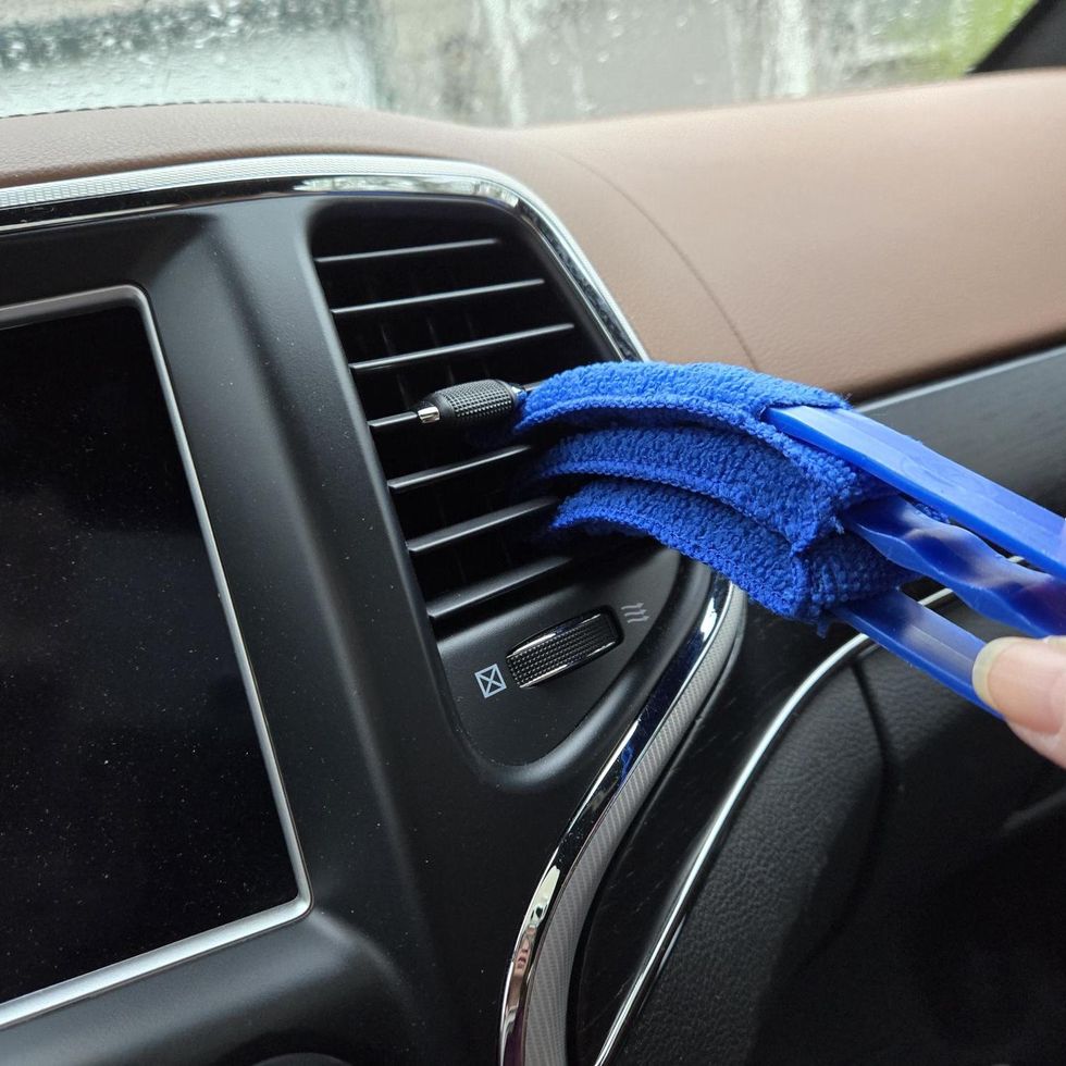 a hand holding a blue object in a car