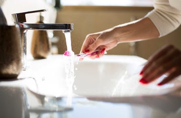 Brushing teeth at a bathroom sink with running water