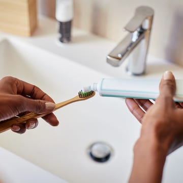 woman holding toothbrush and toothpaste by sink woman holding toothbrush and toothpaste by sink