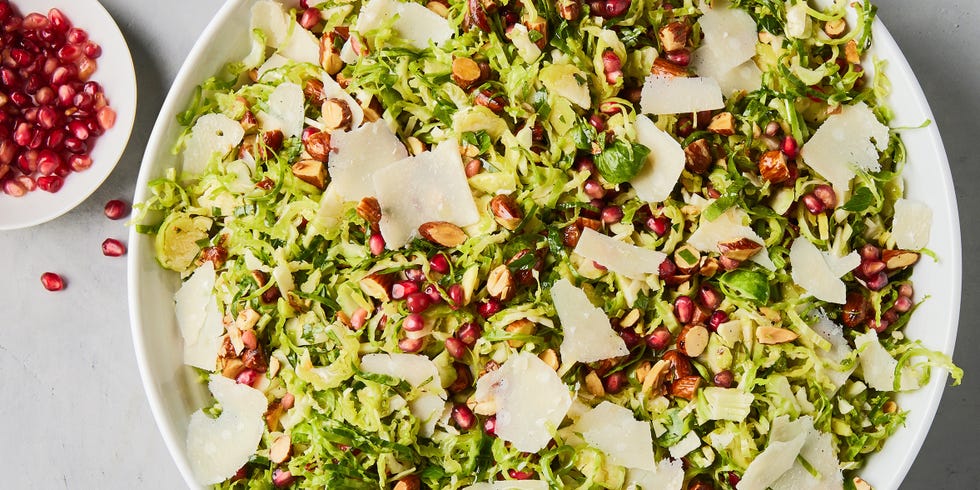 Shredded Brussels sprouts, pomegranate, shredded Parmesan cheese and chopped toasted almonds in a white bowl