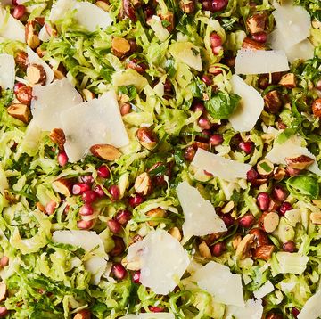shaved brussels sprouts with pomegranates, shaved parmesan, and chopped toasted almonds in a white bowl