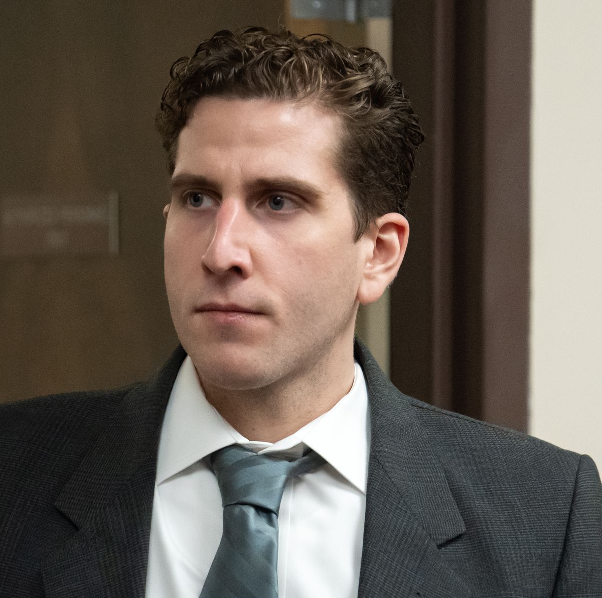 man in a suit and tie standing in a courtroom as he looks left