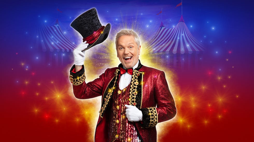 A magician or ringmaster in a glamorous red costume with a black top hat against a circusthemed background
