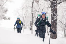 a snowy environment with two hikers making their way through deep snow