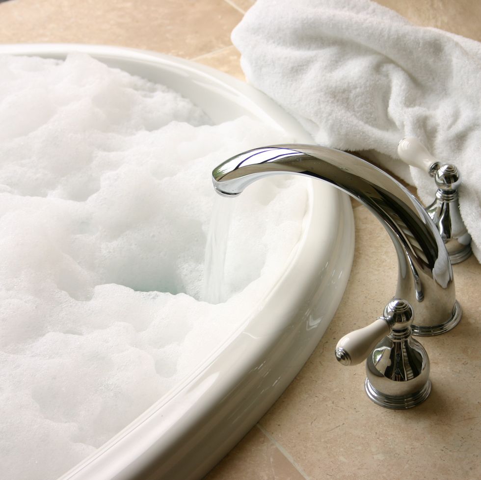 bubble bath with chrome faucet, travertine, towel