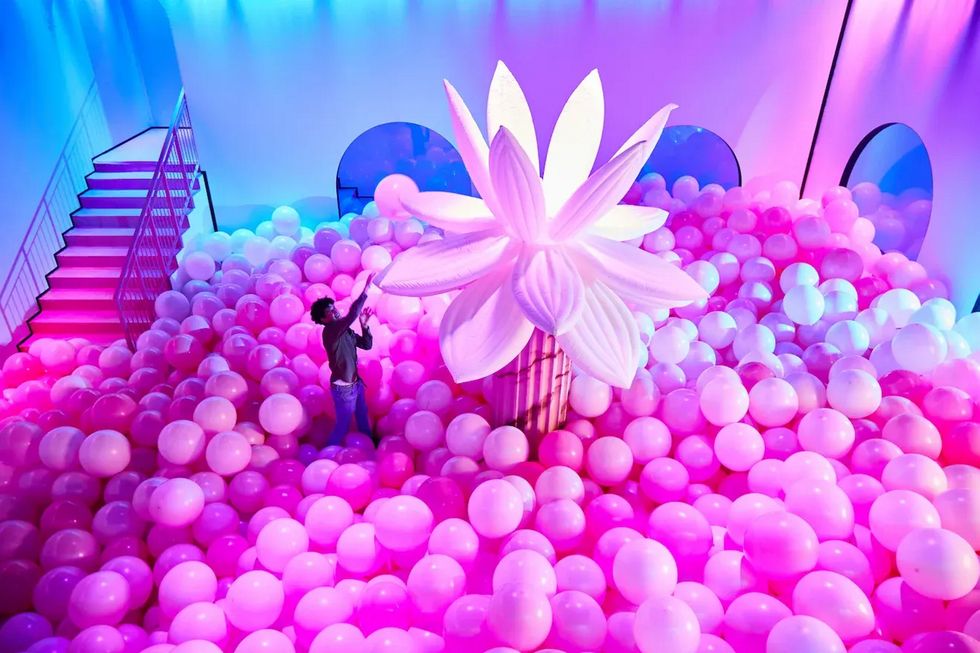 a person standing in front of a large group of pink balls