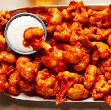fried cauliflower wings tossed in buffalo sauce on a platter with ranch dressing
