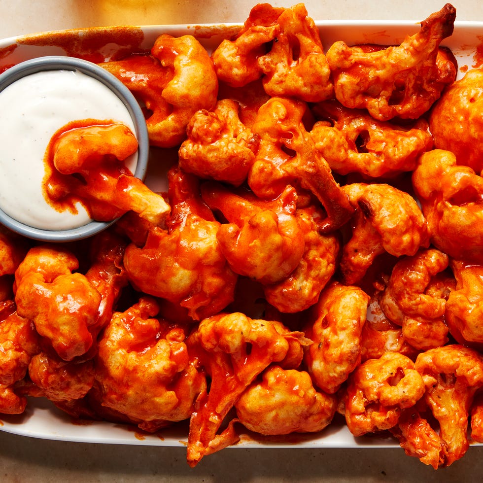 fried cauliflower wings tossed in buffalo sauce on a platter with ranch dressing