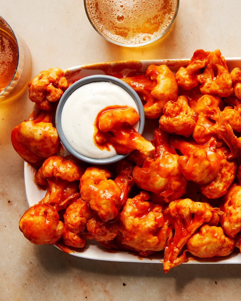 fried cauliflower wings tossed in buffalo sauce on a platter with ranch dressing